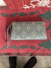 a green and white purse on a rug next to a christmas tree