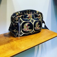 a bag with a paisley pattern on it sits on a wooden shelf