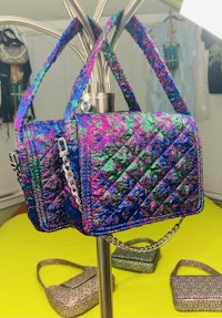 two colorful handbags hanging on a pole
